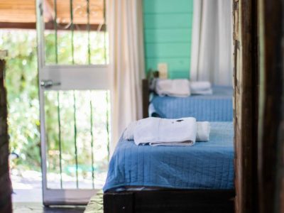 Habitación Cabañas Nono: camas azules, jardín y luz natural.